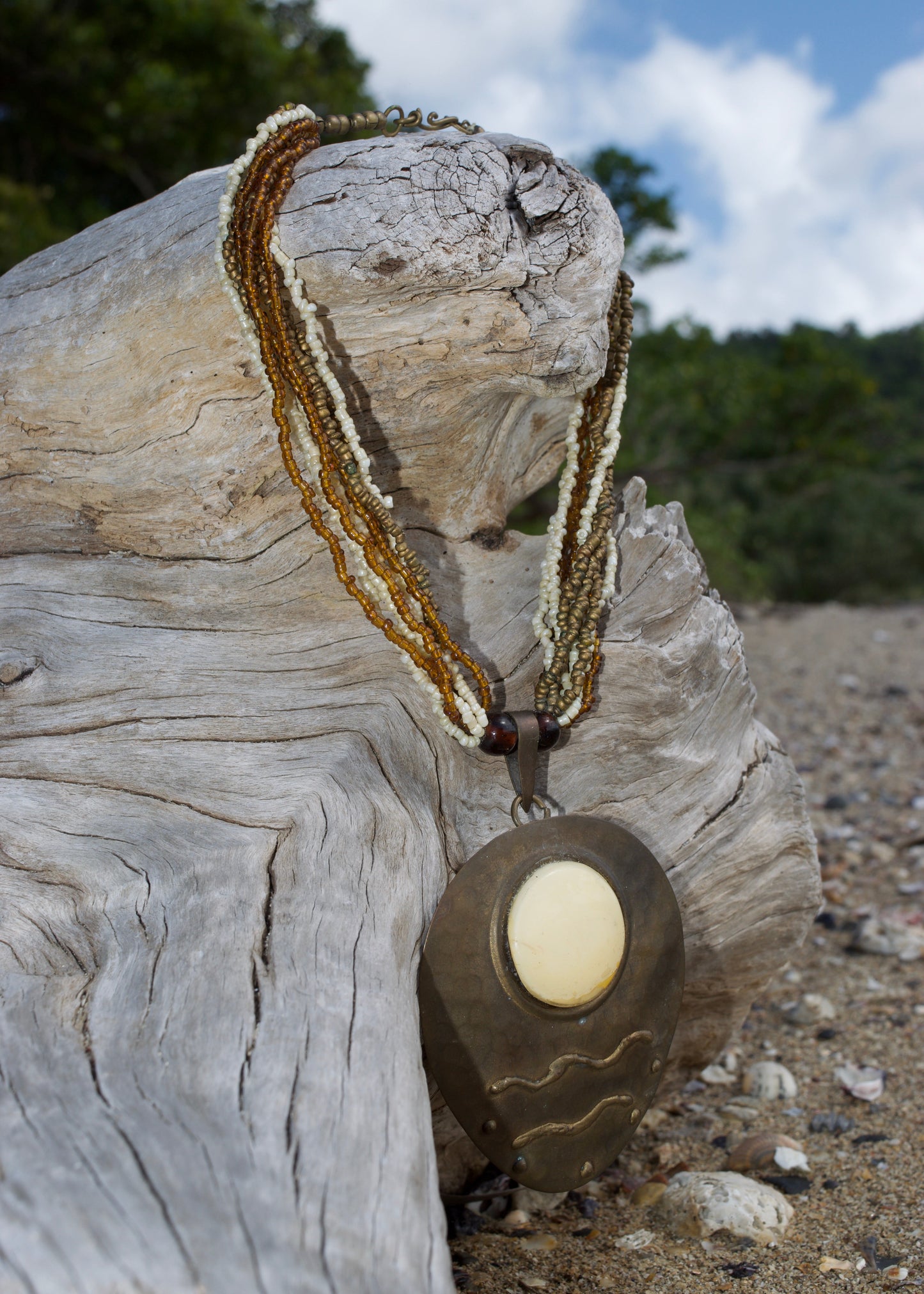 vintage necklace on a piece of driftwood with a blurred natural background