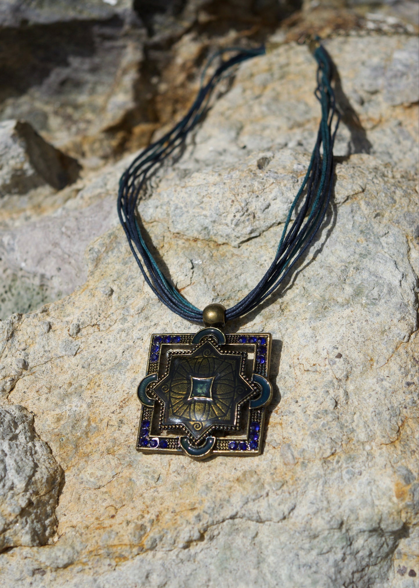 Decorative pendant with blue accents on a stone surface